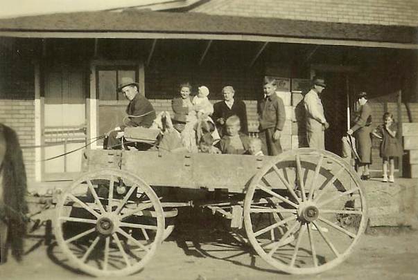 01 Farmer’s Exchange: Wendy in wagon, Ruth and baby Carolyn, Grandma Graves, Donald, Maurice, Marvin, Mr. Melton Hensley, Aunt Minnie and Wyrick girl